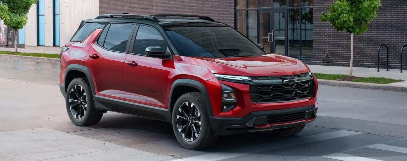 A red 2025 Chevy Equinox for sale parked near a brick building.