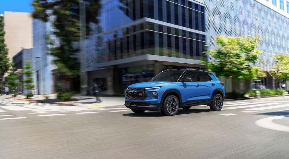 A blue 2024 Chevy Trailblazer RS is driving on a city street.