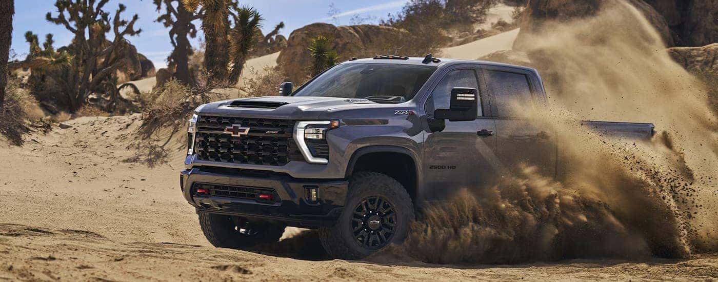 A grey 2024 Chevy Silverado 2500HD ZR2 driving over sandy terrain.