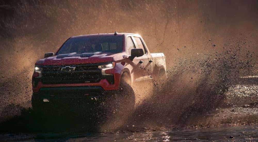 A red 2024 Chevy Silverado 1500 Z71 Trail Boss driving down a dusty trail.