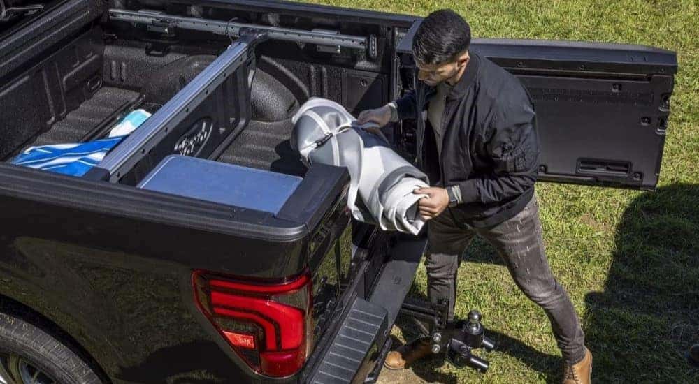 A person loading gear into the bed of a black 2024 Ford F-150.