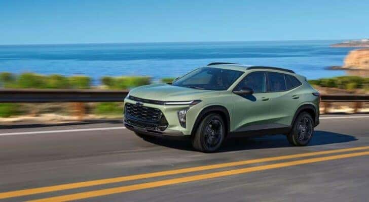 A pale green 2024 Chevy Trax ACTIV driving on a seaside road.