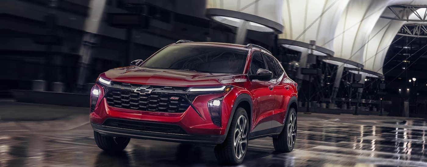 A red 2025 Chevy Trax 2RS driving under lights at night.