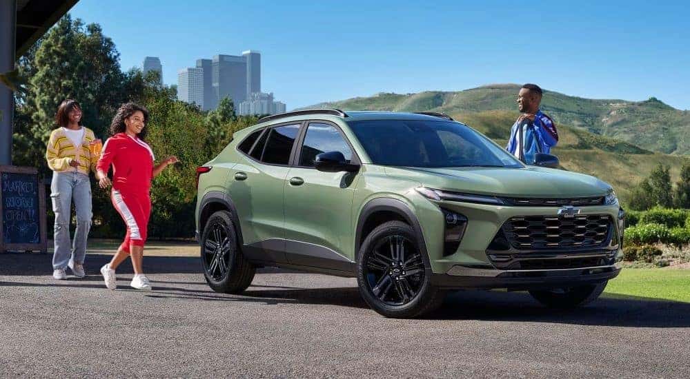 People walking towards a parked green 2024 Chevy Trax LS.