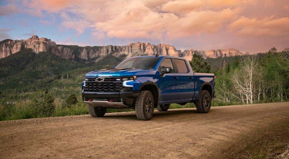 A blue 2024 Chevy Silverado 1500 ZR2 driving off-road on a dirt trail.