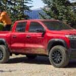 A red 2024 Chevy Colorado Trail Boss parked on a dirt road.