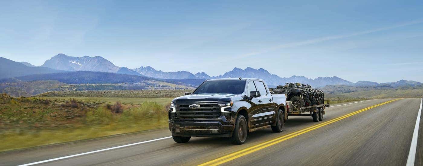 A black 2025 Chevy Silverado 1500 Hight Country towing an ATV.