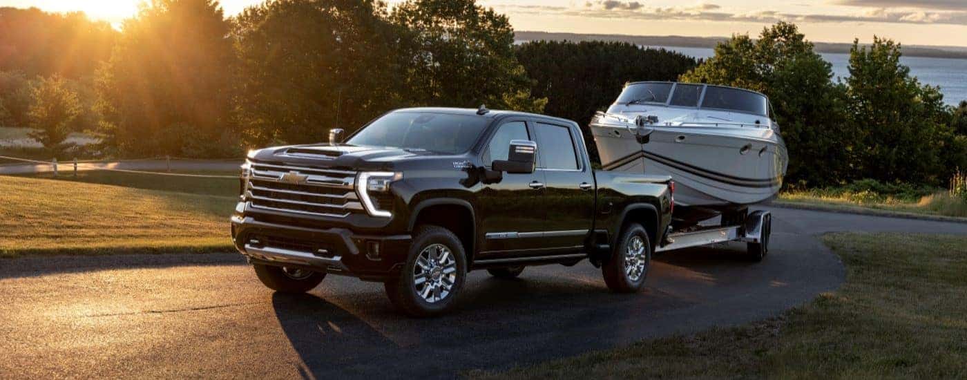 A black 2024 Chevy Silverado 2500 HD High Country towing a boat