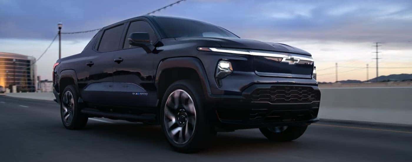 A black 2025 Chevy Silverado EV RST driving on a highway.