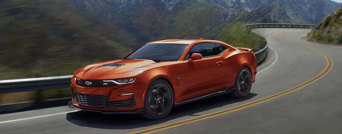 An orange 2024 Chevy Camaro driving after visiting a used Chevy dealer near Wellford.