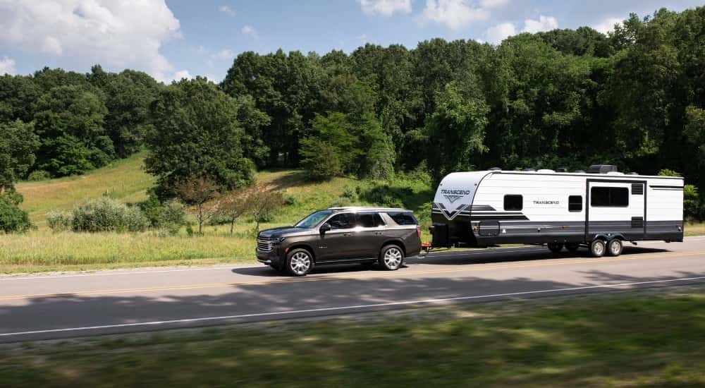 A brown 2021 Chevy Tahoe High Country towing a trailer.