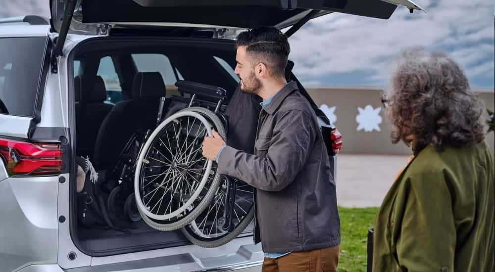 A person loading a wheelchair in a silver 2023 Chevy Traverse.