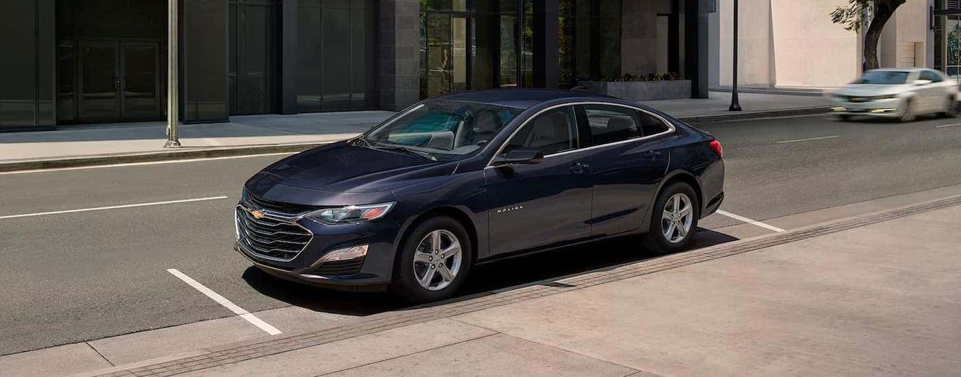 Black 2023 Chevy Malibu parked near a curb by a used car dealer near Duncan.