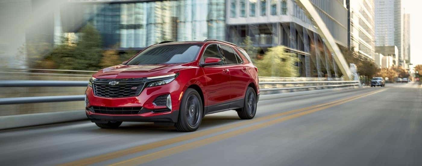 Red 2024 Chevy Equinox RS for sale near Greer driving down a bridge.