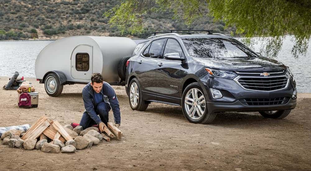 Two people set up a campsite next to their grey 2020 Chevy Equinox