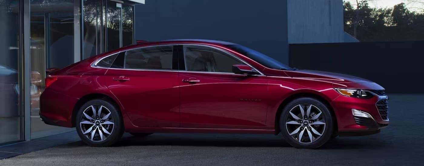 A red 2024 Chevy Malibu parked near a house.