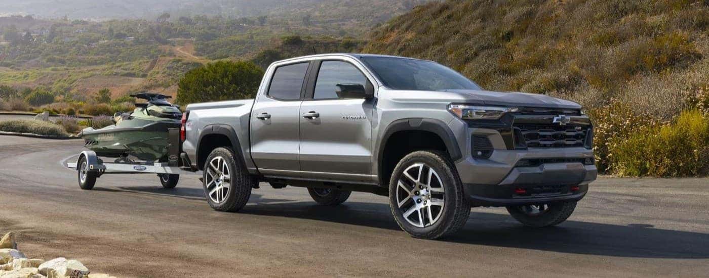 Silver 2025 Chevy Colorado Z71 towing a jetski off-road.