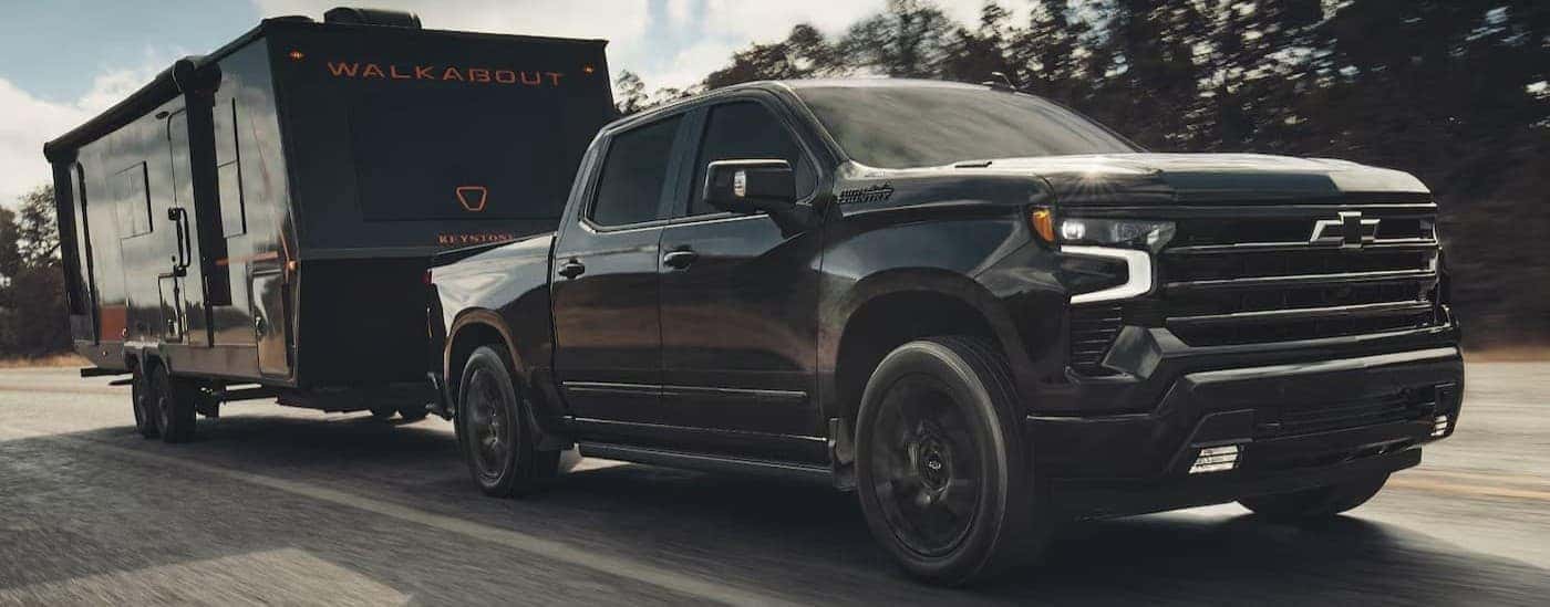 A black 2026 Chevy Silverado 1500 towing a trailer.