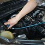 a mechanic hooking up a cable to charge an air conditioner system