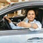 a woman sitting in the driver's seat of a car holding car keys