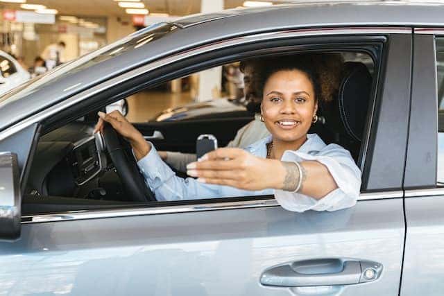 a woman sitting in the driver's seat of a car holding car keys