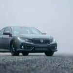 a silver honda on a gravel road against a foggy background