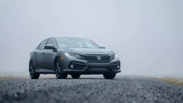 a silver honda on a gravel road against a foggy background