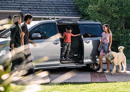 family with a dog getting in a toyota minivan