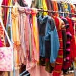 brightly colored scarves, handbags, and clothes on rack at boutique store