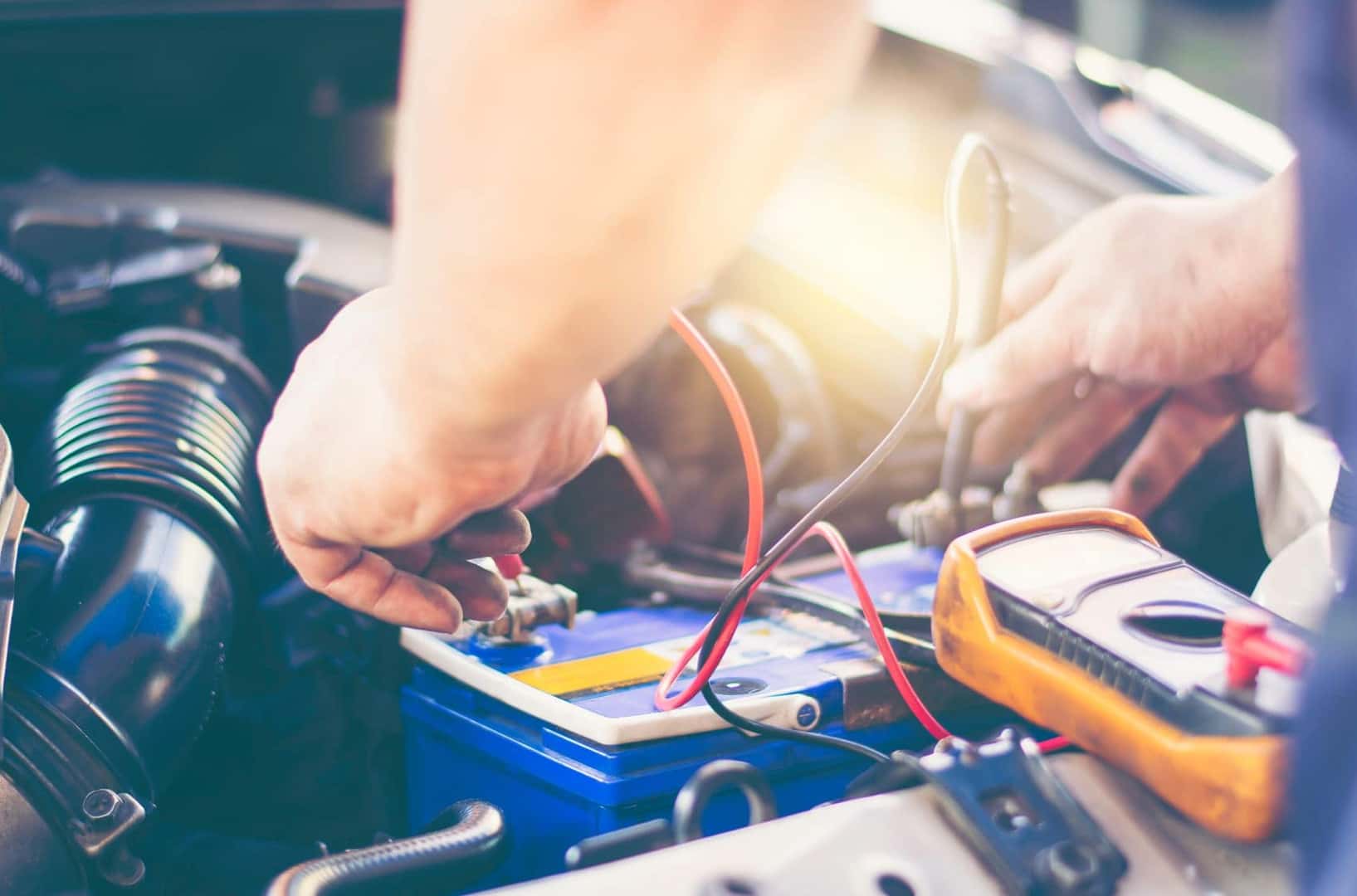 Technician replacing car battery;