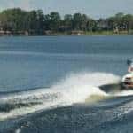 guy doing a trick on a wakeboard behind a super air nautique boat