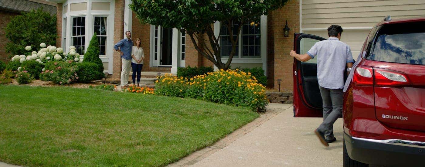 Two parents watch on as their son gets into a red 2020 Chevy Equinox.