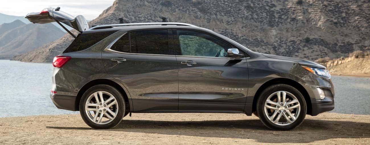 A grey 2020 Chevy Equinox is parked in front of a lake and mountains after winning the 2020 Chevy Equinox vs 2020 Mazda CX-5 comparison.
