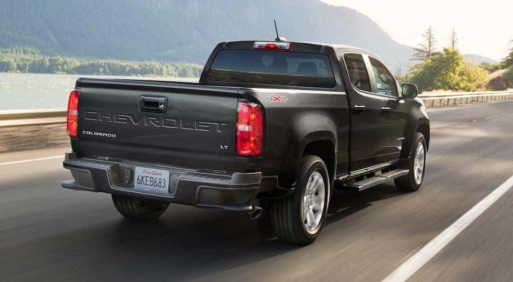 A black 2021 Chevy Colorado is driving past a lake.