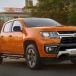 An orange 2021 Chevy Colorado is driving on a city street after leaving a Chevy dealer in Bethlehem, PA.