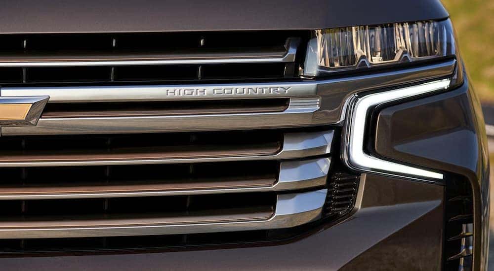 A close up of the grille and headlight are shown on a grey 2021 Chevy Tahoe High Country.
