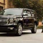 A family is walking away from a black 2019 Chevy Suburban in a driveway.