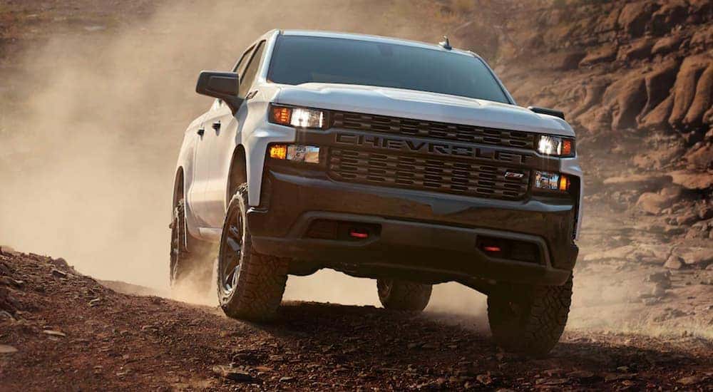 A white 2021 Chevy Silverado 1500 is off-roading and kicking up dirt after leaving a Pennsylvania Chevy dealer.