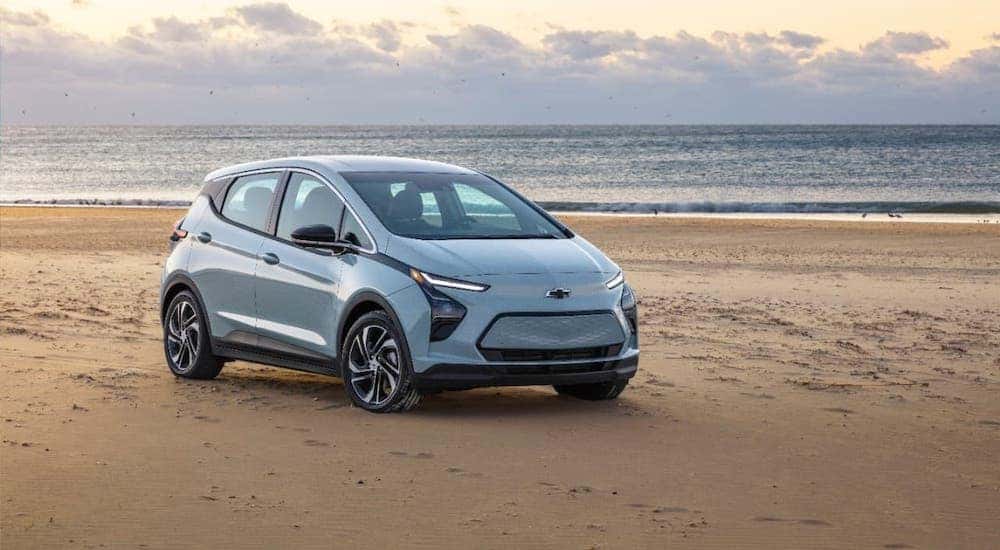 A pale blue 2022 Chevy Bolt EV is parked on a beach.