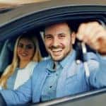 A couple is shown sitting in the front seats of a car at an Allentown used car dealer.