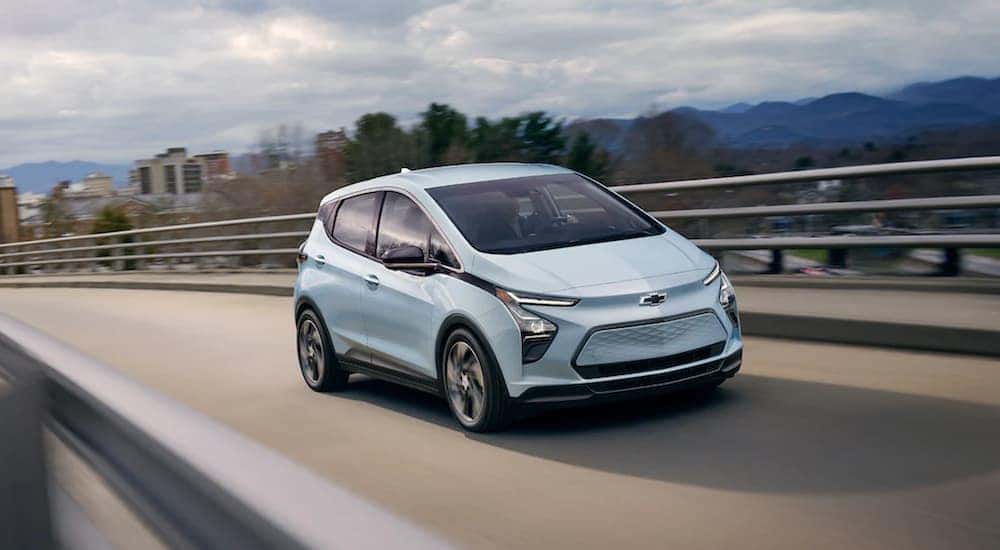 A baby blue 2022 Chevy Bolt EV is driving along an open road after leaving a Pennsylvania electric car dealer.