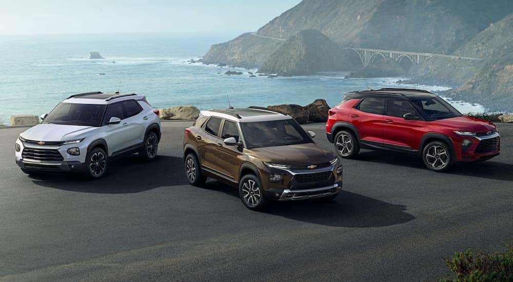 A white, a gold, and a red 2022 Chevy Trailblazer are shown parked in front of the ocean.