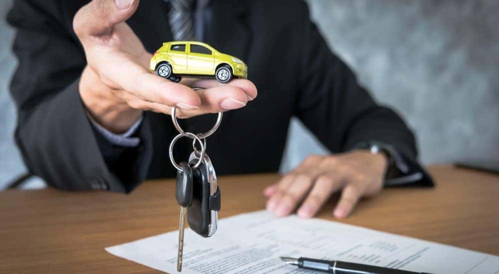 A man is shown holding a toy car and keys during a Chevy lease deal agreement.