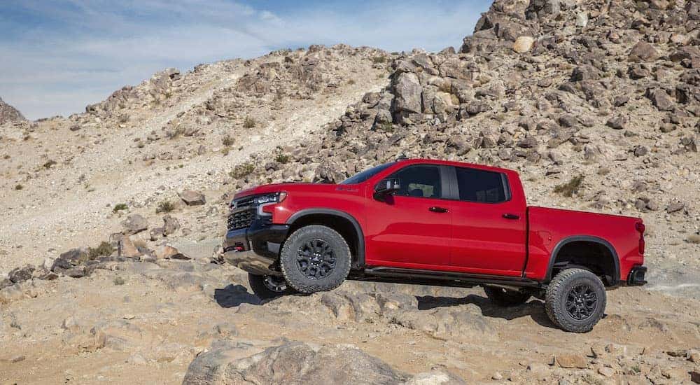 A red 2022 Chevy Silverado ZR2 is shown from the side while off-roading.