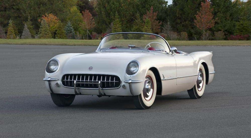 A white 1954 Chevy Corvette is shown from the front parked in a lot.