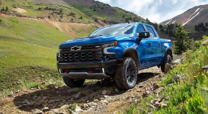 A blue 2022 Chevy Silverado 1500 ZR2 is shown driving on a dirt path.