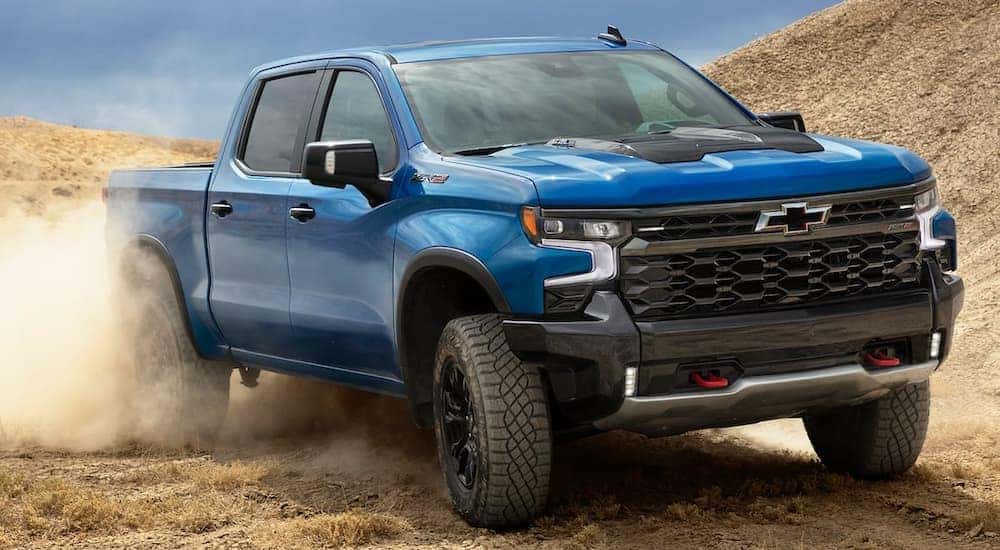A blue 2022 Chevy Silverado ZR2 is shown driving on a dusty trail.