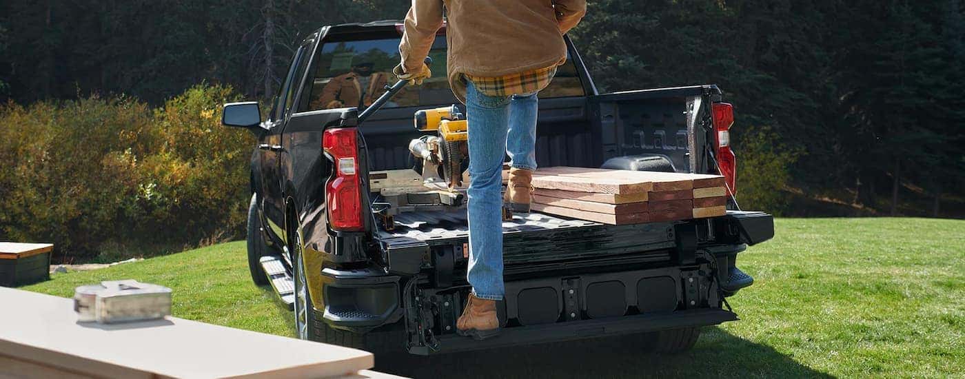 A man is shown getting supplies out of the bed of a black 2022 Chevy Silverado 1500.
