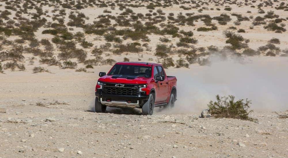 A red 2022 Chevy Silverado 1500 ZR2 is shown from the front while driving off-road.