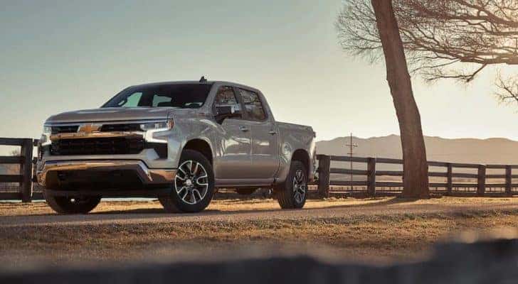 A grey 2022 Chevy Silverado 1500 Custom for sale near Allentown, PA is shown parked near a farm.